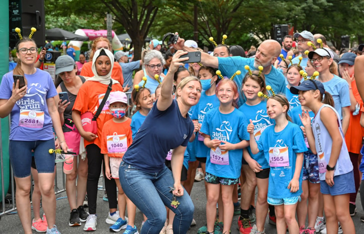 Kristen Cheman taking a selfie with Girls on the Run participants before the Spring 2022 5K at Ballston.